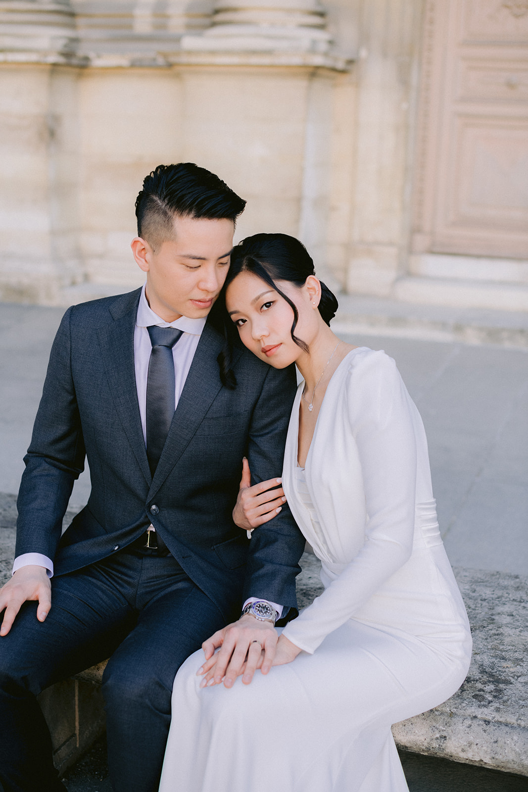 Couple sitting on a bench, with the bride looking at the camera